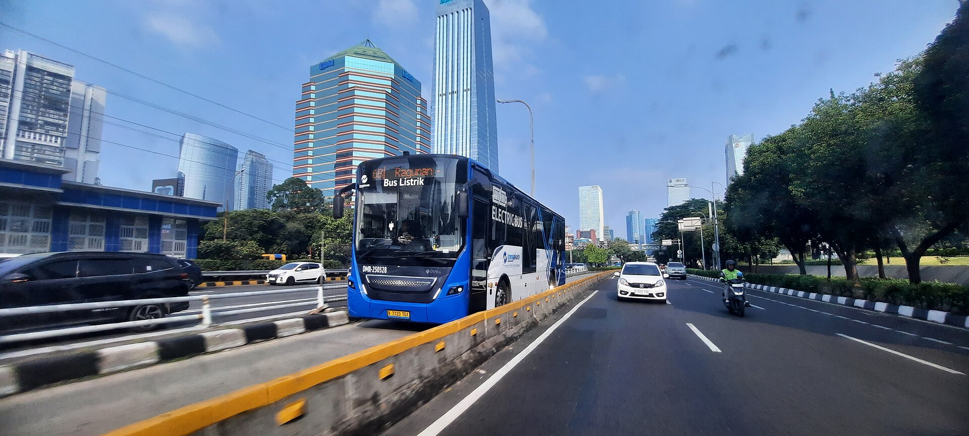 Bus listrik Transjakarta melintas di jalur busway dengan latar gedung-gedung Sudirman, Jakarta
